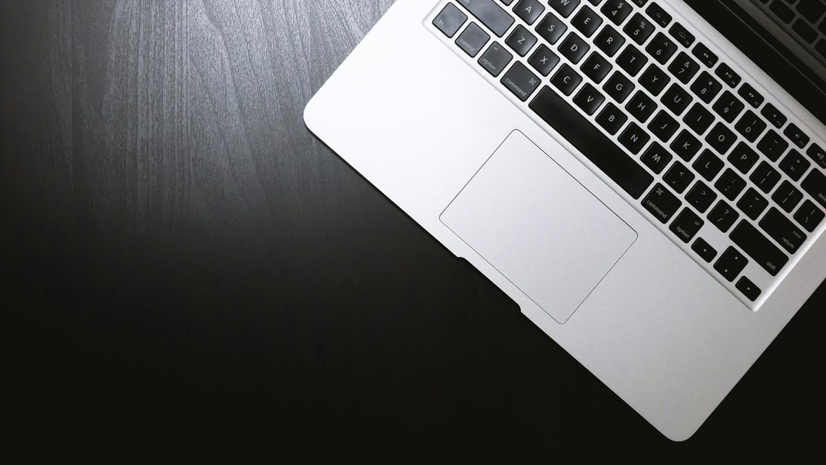 MacBook plateada sobre un escritorio de madera oscuro