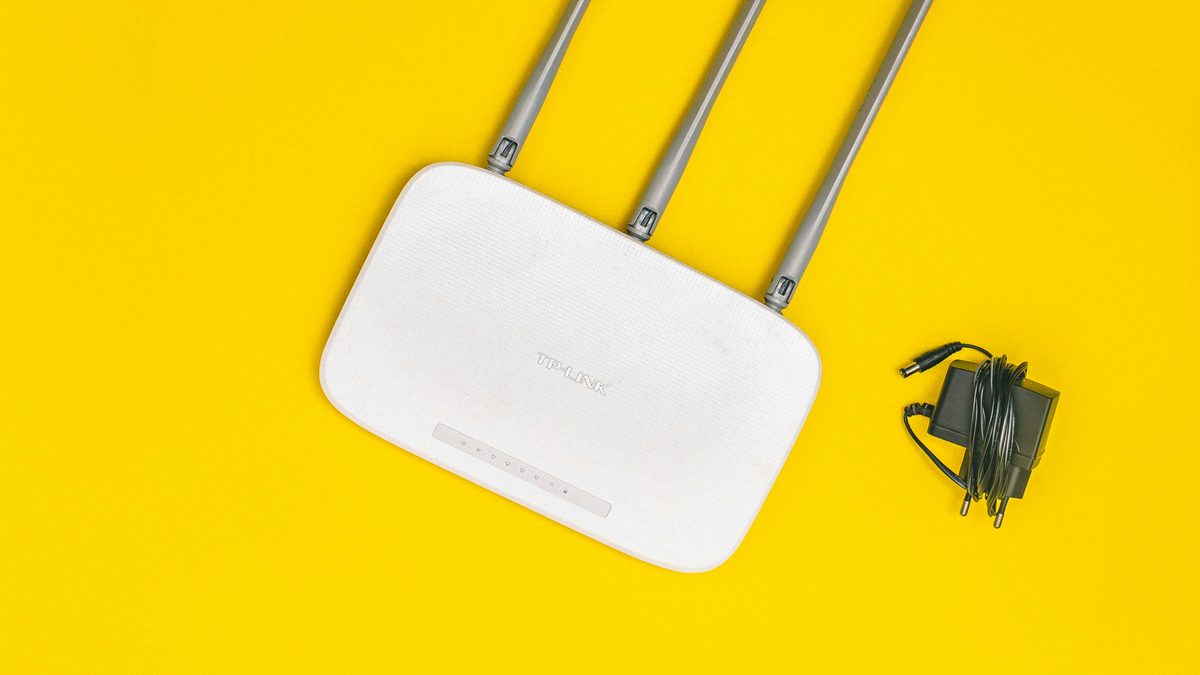 Router Wi-Fi blanco con antenas sobre fondo amarillo